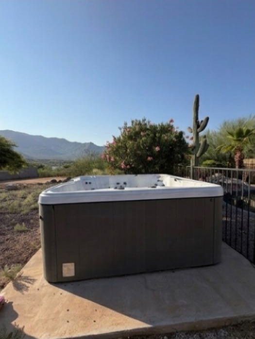 Large hot tub on a concrete pad in a desert backyard with mountain views