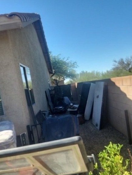 Narrow side yard blocked with old doors, scrap metal and household items